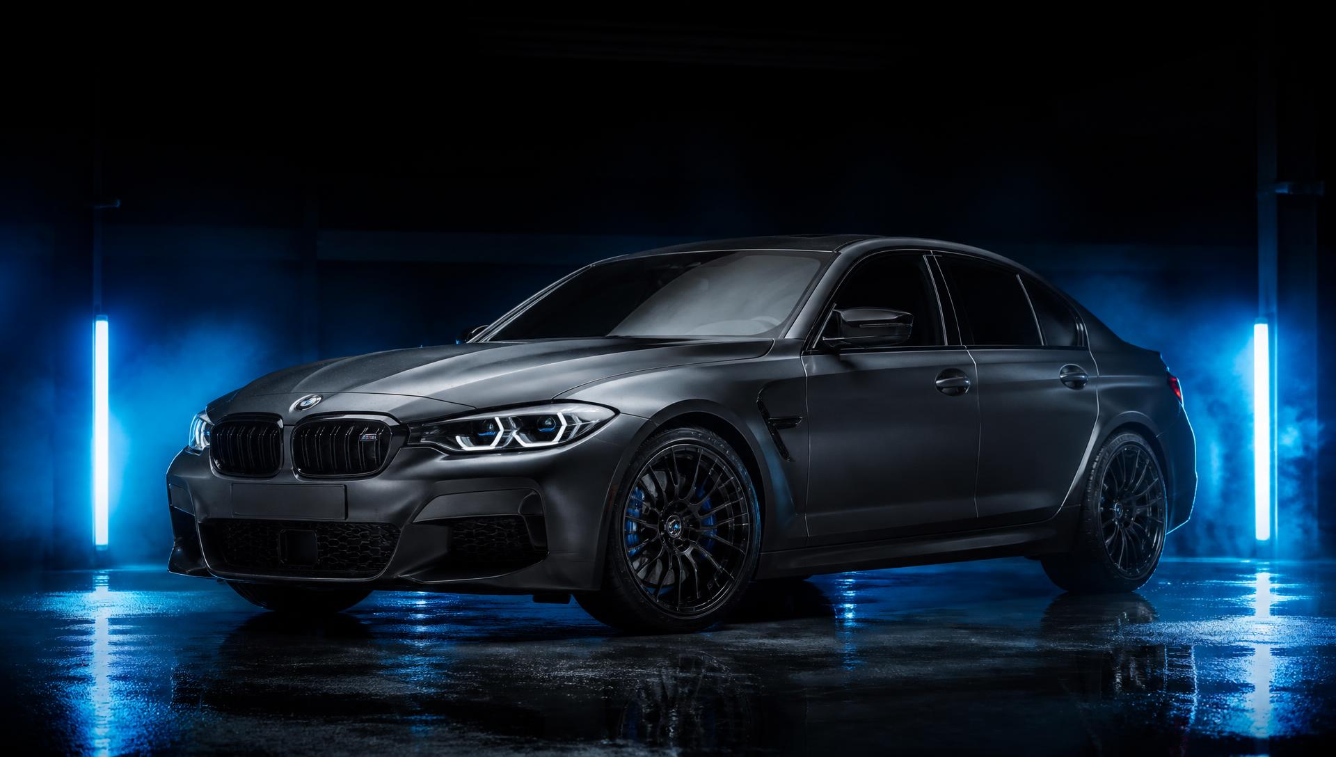 Dark performance sedan with tinted windows in a studio garage lit by cold blue light